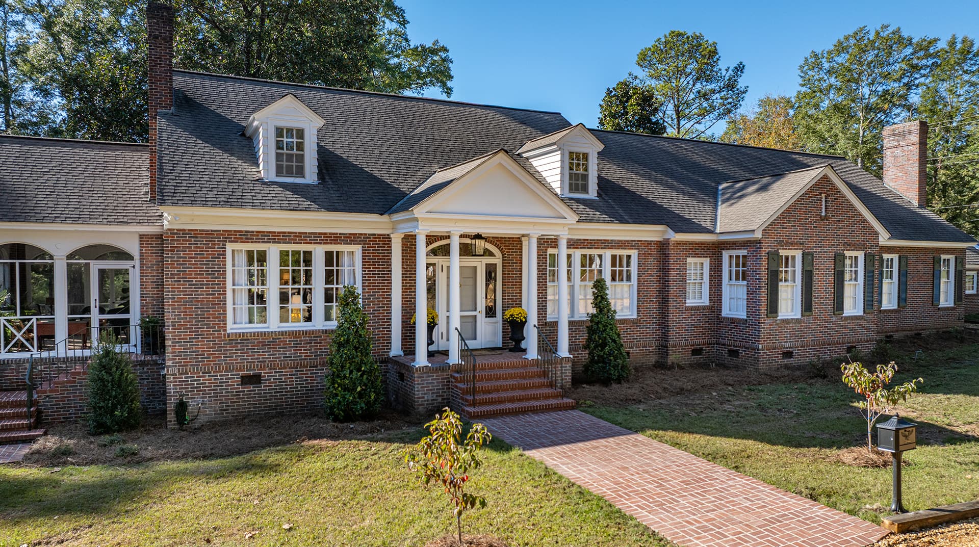 A charming brick house with a front porch and landscaped yard.